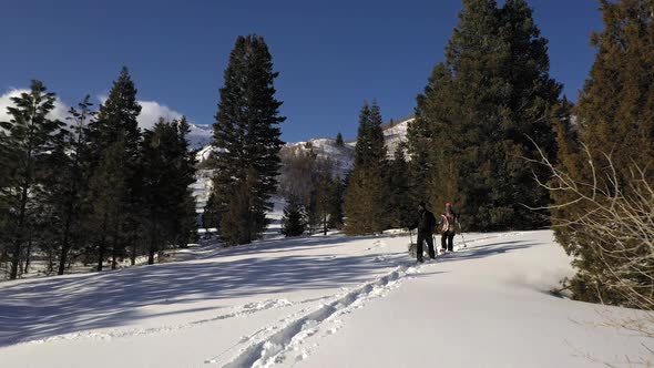 Aerial view of couple hiking down trail in the snow