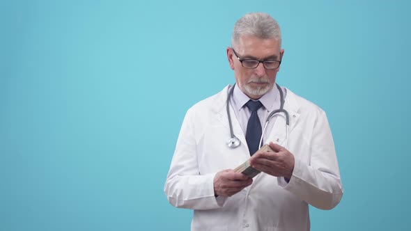 Doctor is a Man in Robe and Tie Beats of Dollar Bills on Palm in the Studio Blue Background