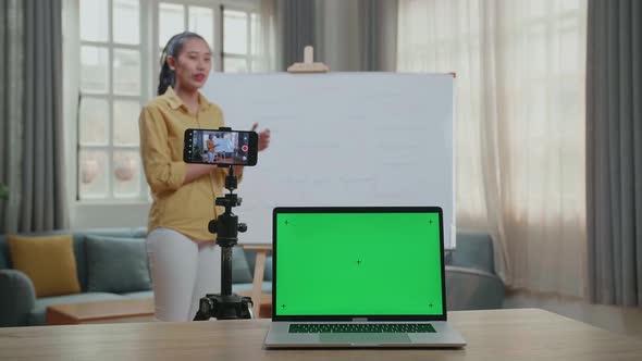 Asian Female Teacher With Green Screen Laptop Shoots Video By Smartphone While Teaching English