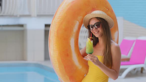 Beautiful Slender Tanned Caucasian Blonde Woman in Sunglasses Drinks Fruit Juice By Pool in Spa