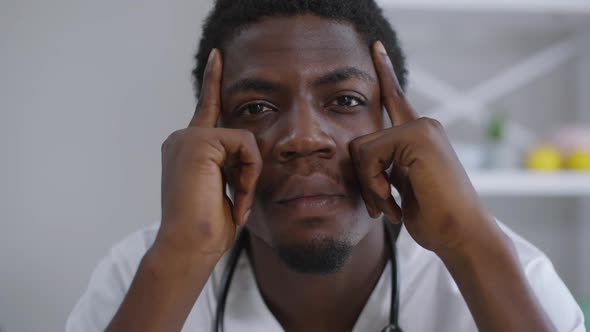 Front View Headshot Tired African American Doctor Rubbing Temples Looking at Camera