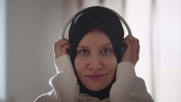 Pretty Woman in Hijab Puts Headphones on Her Head