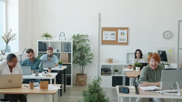 Happy Men and Women Having Fun in Office Fighting with Toy Guns and Throwing Paper Balls