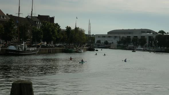 Wide shot showing group of people paddling kayak on Trave river in Lübeck during sunset