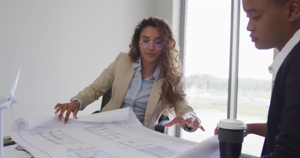 Biracial female architects talking and checking architects plans in modern office