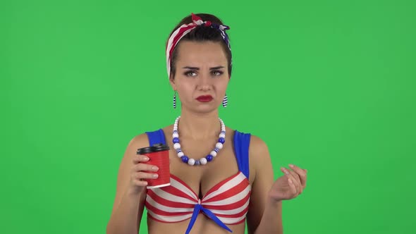 Portrait of Beautiful Girl in Swimsuit Drinking Unpalatable Coffee and Is Disgusted. Green Screen