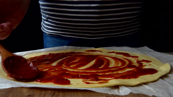 The chef cooking a pizza with tomato sauce.