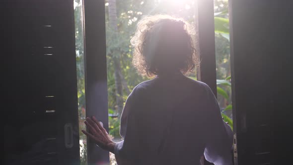 Back View of Woman Opening a Window and Stretching