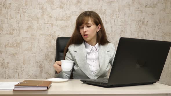 Beautiful Girl Sitting in Chair in Office and Typing on Laptop