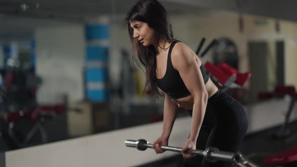 Side View Fit Positive Middle Eastern Sportswoman Pulling Up Barbell to Belly Training Muscles in