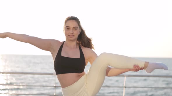 Flexible Female Gymnast Doing Acrobatic Tricks at Sunrise on the Beach