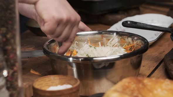 Chef in the Restaurant Mixes Veggie Salad with Spoon in Shiny Saucepan