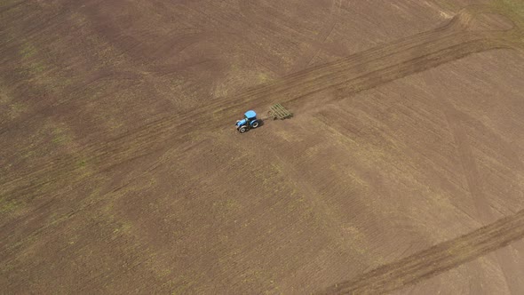 Aerial View of a Tractor with a Cultivator Working in the Field