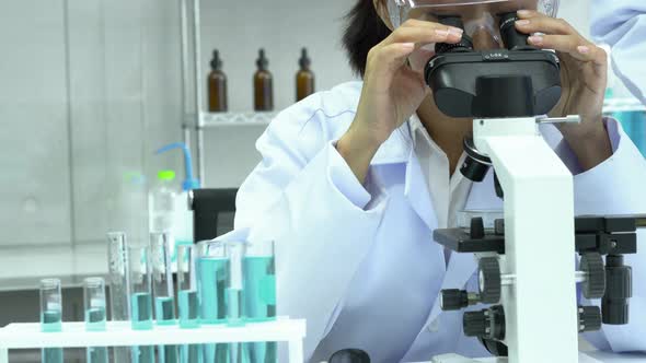 Woman looking microscope in laboratory