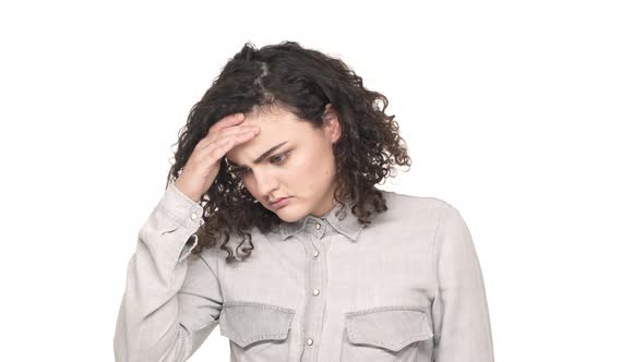 Portrait of Tired Woman with Curly Hair Touching Her Forehead and Feeling Sick or Having Headache