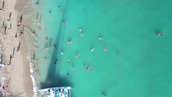 Stunning 4k aerial overhead of families enjoying the sun, surf and sand as well as crystal blue wate