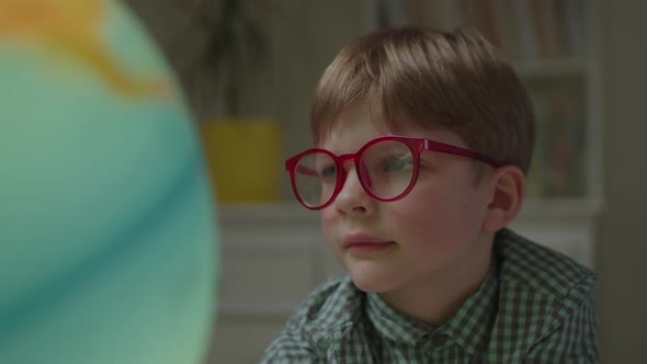 Close Up of Curious Preschool Boy Studying Earth Globe