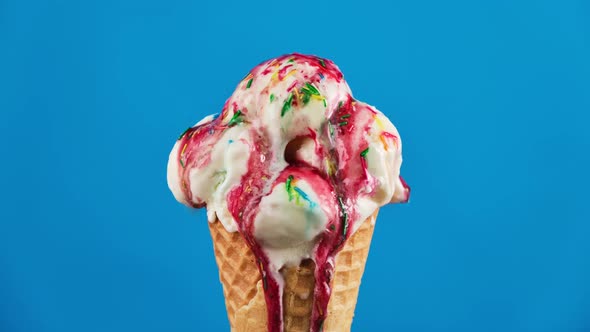 Vanilla Ice Cream with Strawberry Topping and Sprinkles in Waffle Cone Melting