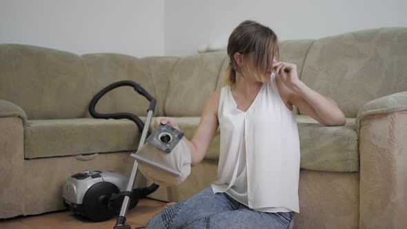 Allergy Dust, Woman Sitting on Floor Sneezes Due To Dust After Cleaning Room with Vacuum Cleaner