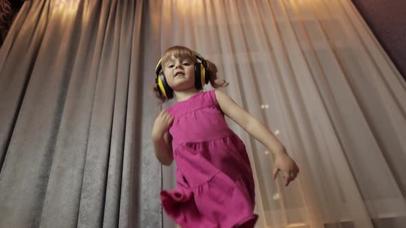 Little Child Girl in Wireless Headphones Enjoying Listen Music. Dancing at Home