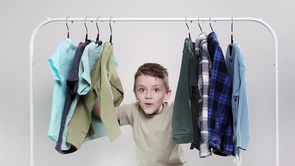 The little boy appears from behind the clothes rack.