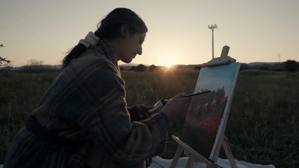 Young girl paints the picture on canvas in the countryside