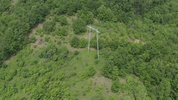 Electricity pylon and transmission cables over the forest 4K drone video