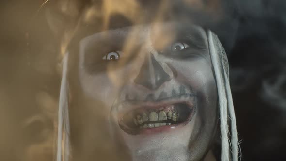 Portrait of Scary Guy in Thematic Costume of Halloween Skeleton Exhaling Cigarette Smoke From Mouth