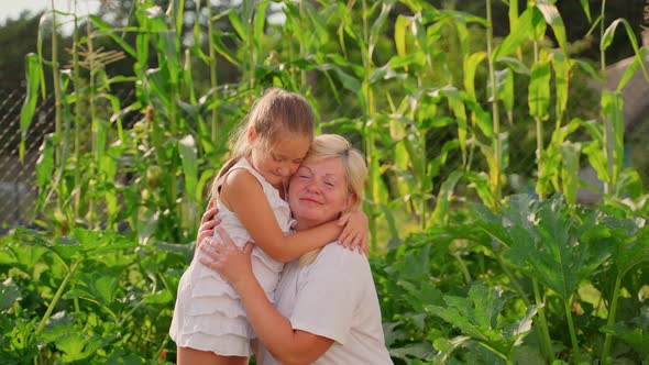 Portrait grandmother and granddaughter hugging in garden outdoors. Two females