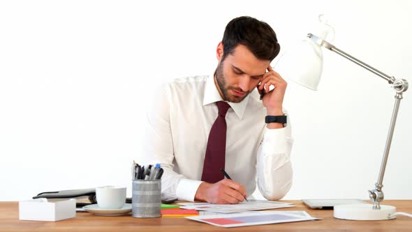 Businessman working at his desk and talking on mobile phone