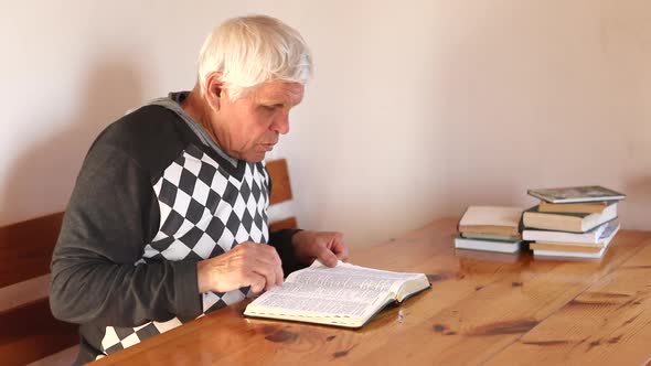 Senior Man Praying Reading an Old Bible in His Hands