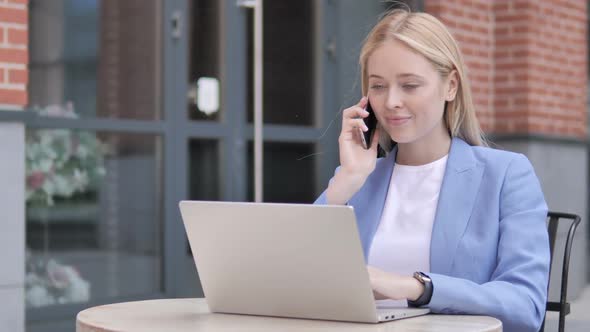 Young Businesswoman Talking on Phone Sitting Outdoor