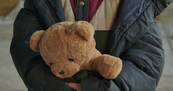 Close-up of Homeless Girl's Hands Holding Teddy Bear