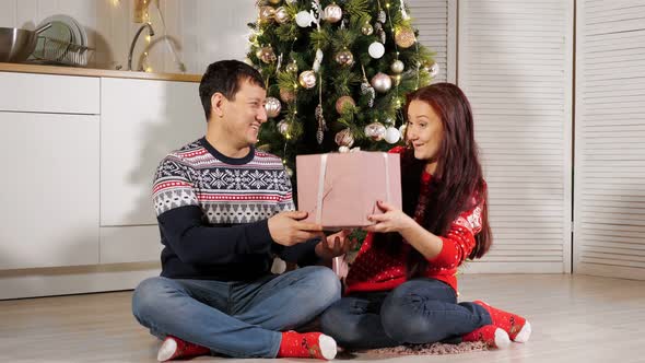 Wife Gets Husband New Year Gift Sitting on Kitchen Floor
