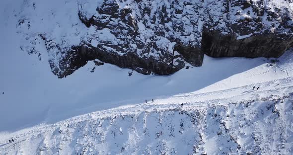 A Group of People Climb a Snow Path in the Gorge