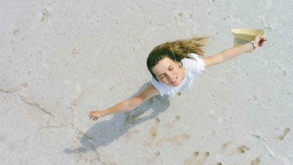 Beautiful happy young girl is spinning on a dry salt lake