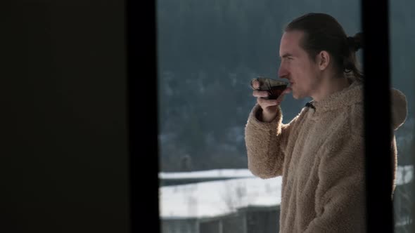 Man drinking tea on balcony.