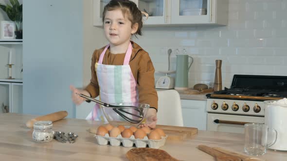 Little Girl Shows Thumb-up Near Table in Light Kitchen