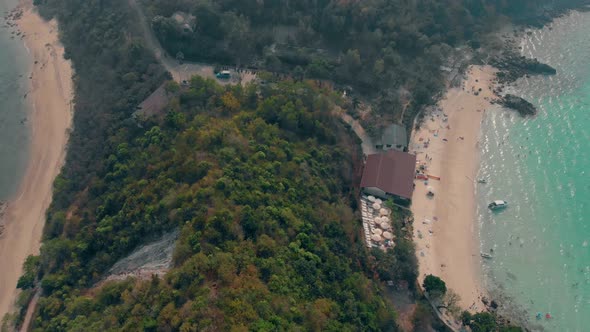 Sand Beach with Resting People Between Green Hill and Ocean