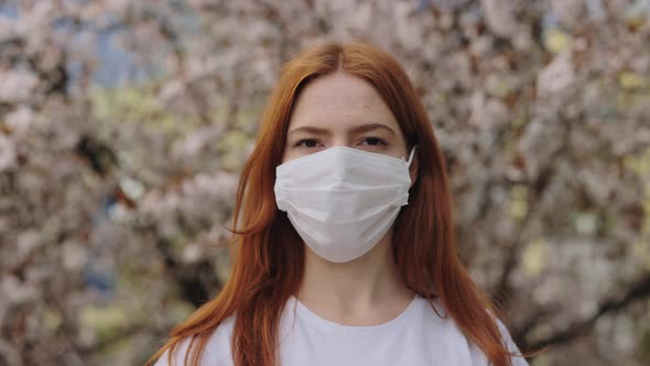 Calm Young Woman in Mask Looking at Camera at Spring Park