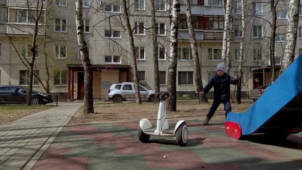 Little Boy Funny Playing on the Playground with the Help of New Technology Segway Gadget in Early