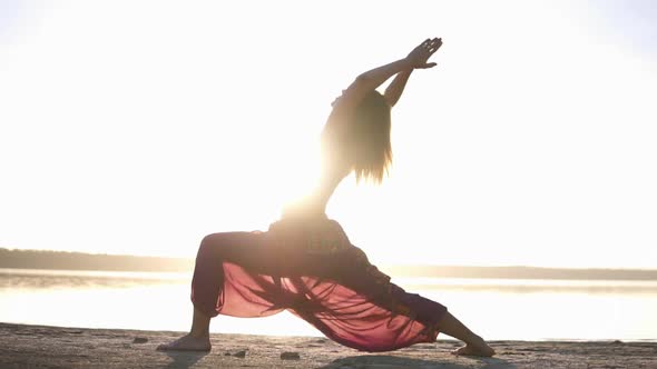 Side View of Attractive Young Woman Practicing Yoga in Warrior Pose Virabhadrasana on Seashore