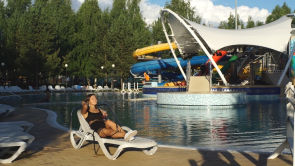 Girl Drinking Juice On a Lounger By The Pool