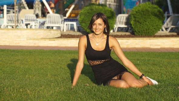 Beautiful Girl Sitting On Grass And Smiling