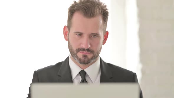 Young Businessman Celebrating Success on Laptop