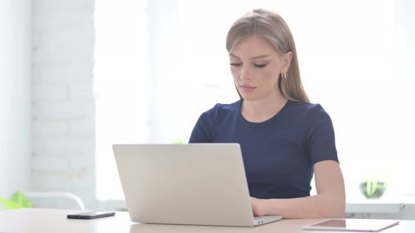 Woman Pointing at Camera While Using Laptop