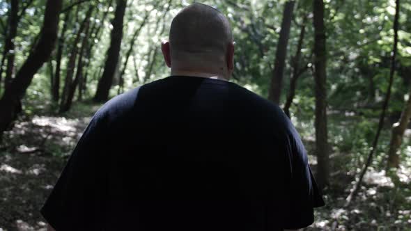 A Man Walks In Trees With Sunlight Shining Through The Forest