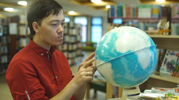 Male College Student Looking At a Globe