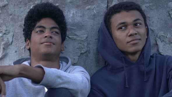 Two African-American homeless teen boys sitting on street