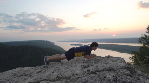 Man Doing Exercise At The Press On Top Of The Mountain